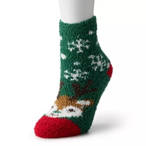 A green fuzzy sock with a festive reindeer and snowflake design featuring red accents on the toe and heel.