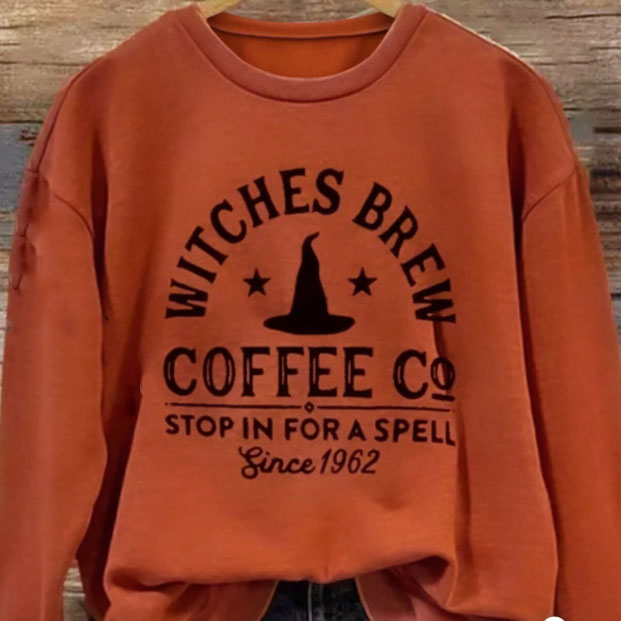 Orange sweatshirt with \“Witches Brew Coffee Co. Stop in for a Spell Since 1962\“ printed on it, featuring a witch's hat and star design.