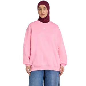 A person is wearing a pink Adidas sweatshirt and blue jeans, along with a dark maroon hijab.
