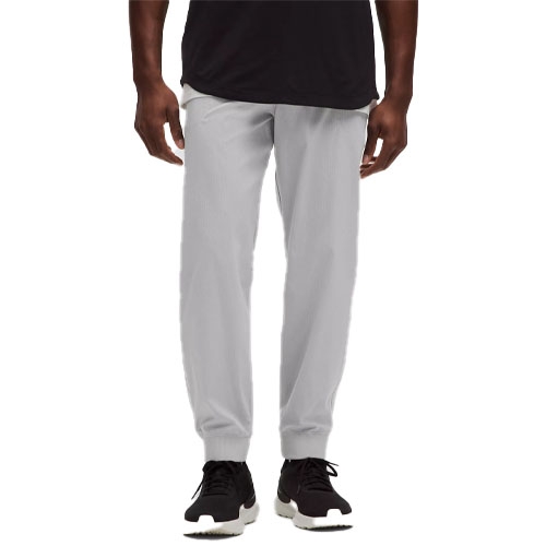 A person is wearing light gray jogger pants and black sneakers paired with a black shirt.