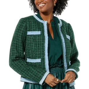 A woman is wearing a green tweed jacket with light blue trim over a green dress.