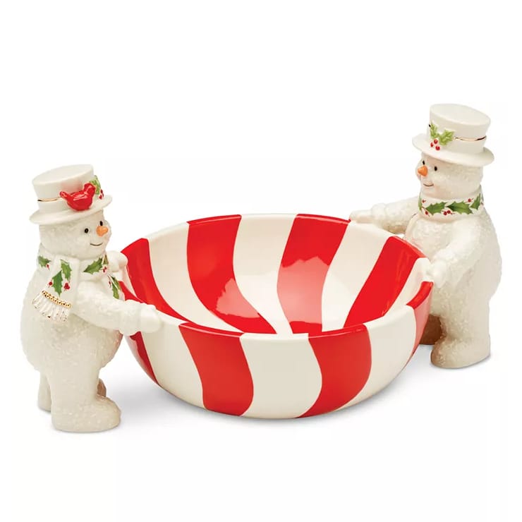 The Lenox Snowmen Candy Dish features two snowmen in white with red scarves, holding a bowl decorated with red and white stripes, reminiscent of a peppermint candy.