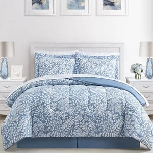A bedding set featuring a light blue and white floral pattern, including a comforter, two pillow shams, a flat sheet, a fitted sheet, two pillowcases, and a bed skirt. The room decor includes lamps, floral arrangements, and abstract wall art.