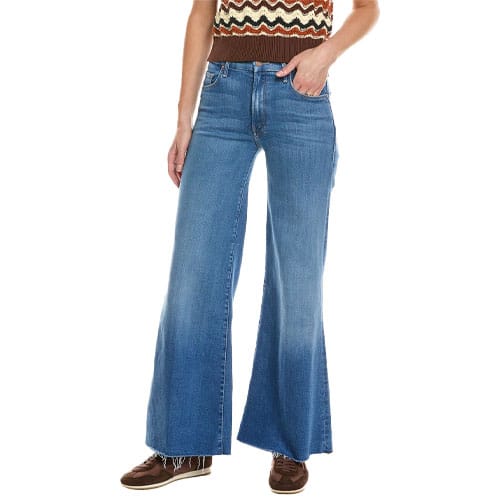 Woman wearing high-waisted, wide-leg blue jeans paired with a sleeveless, patterned top and brown shoes.