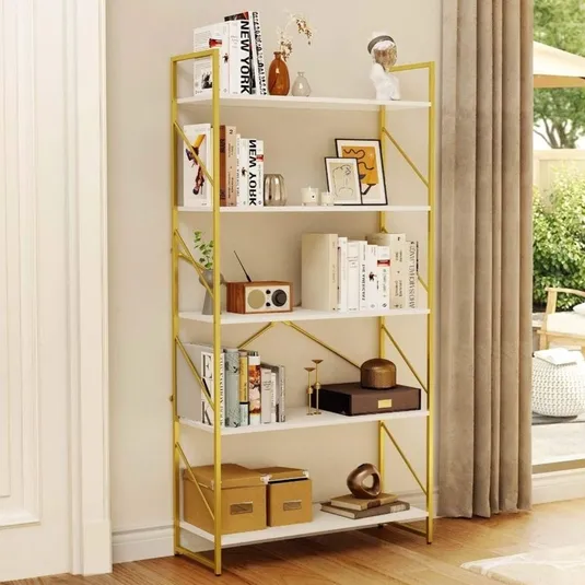 A white and gold bookshelf is adorned with books, decorative items, and storage boxes, placed beside a floor-length curtain in a room with wooden flooring, leading to an outdoor patio.