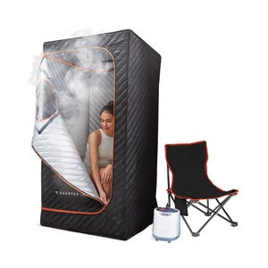 A portable, black quilted sauna tent with a zippered door and steam vent, accompanied by a steam generator and a foldable chair with red trim.