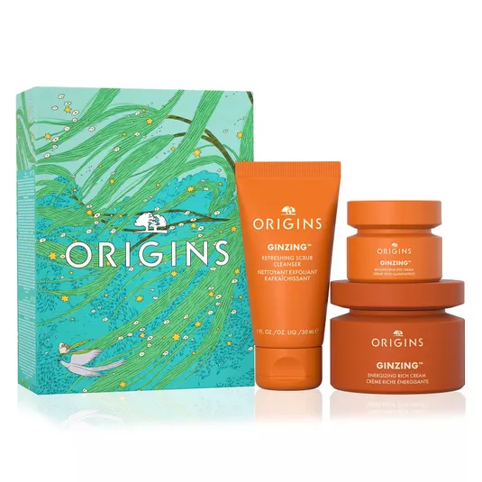 Origins GinZing skincare set, featuring a Refreshing Scrub Cleanser, Brightening Eye Cream, and Energizing Rich Cream, presented in a decorative box with a foliage design.