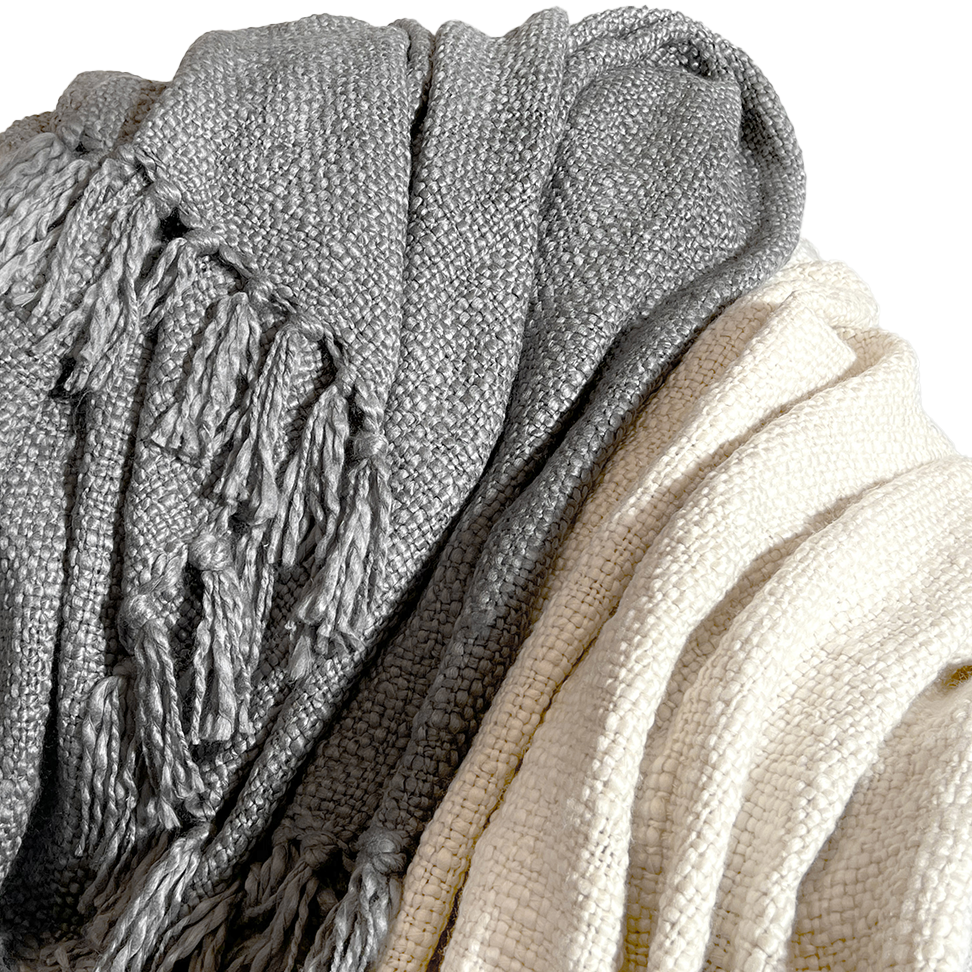 Two woven throw blankets, one in shades of gray and the other in cream, both with fringe detailing.