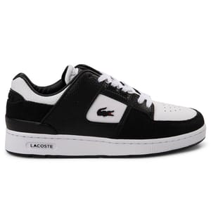 The Lacoste Women's Court Cage Athletic Shoe features a black and white color scheme with a leather upper, signature crocodile logo on the side, and a cushioned white sole for comfort and style.