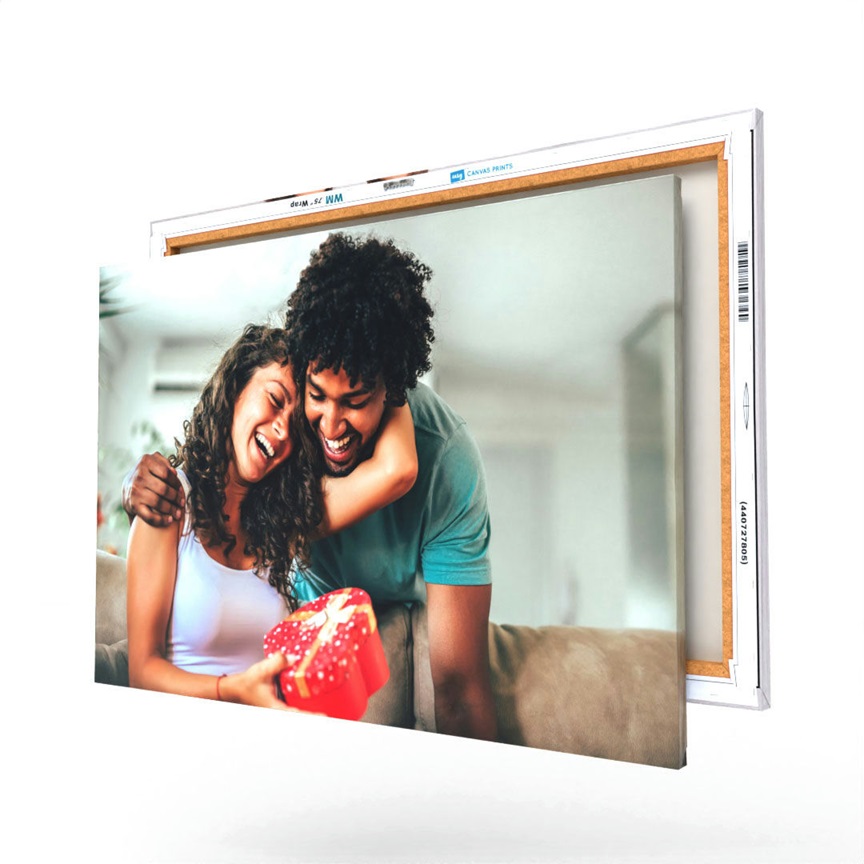 A canvas print featuring a joyful moment between a couple, with one holding a red heart-shaped gift box, shown on a mounted wooden frame.
