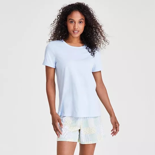 A woman is wearing a light blue t-shirt and patterned white shorts.