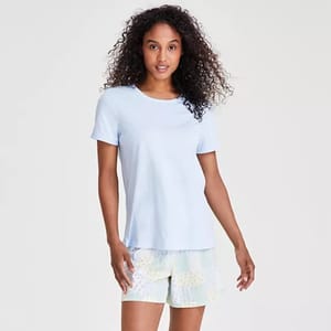 A woman is wearing a light blue t-shirt and patterned white shorts.