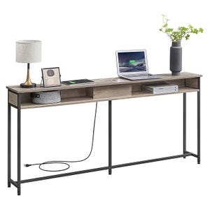 A narrow console table with a wooden surface and black metal frame, featuring a lamp, framed photo, laptop, plant vase, and storage space.