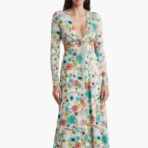 A long-sleeved maxi dress featuring a cutout waist detail and a floral pattern in a mix of vibrant colors on a white background.