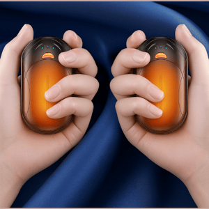 Two hands are holding orange, oval-shaped hand warmers against a blue fabric background.