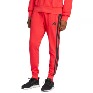 Adidas 3-Stripes French Terry Pants in bright red feature black stripes on the sides, a small logo on the thigh, an elastic waistband, and cuffs. They are paired with black sneakers for a casual look.