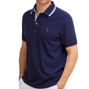 A navy US Polo Assn. polo shirt with a small polka dot pattern features a contrasting collar and placket with light blue detailing and a red logo on the chest.