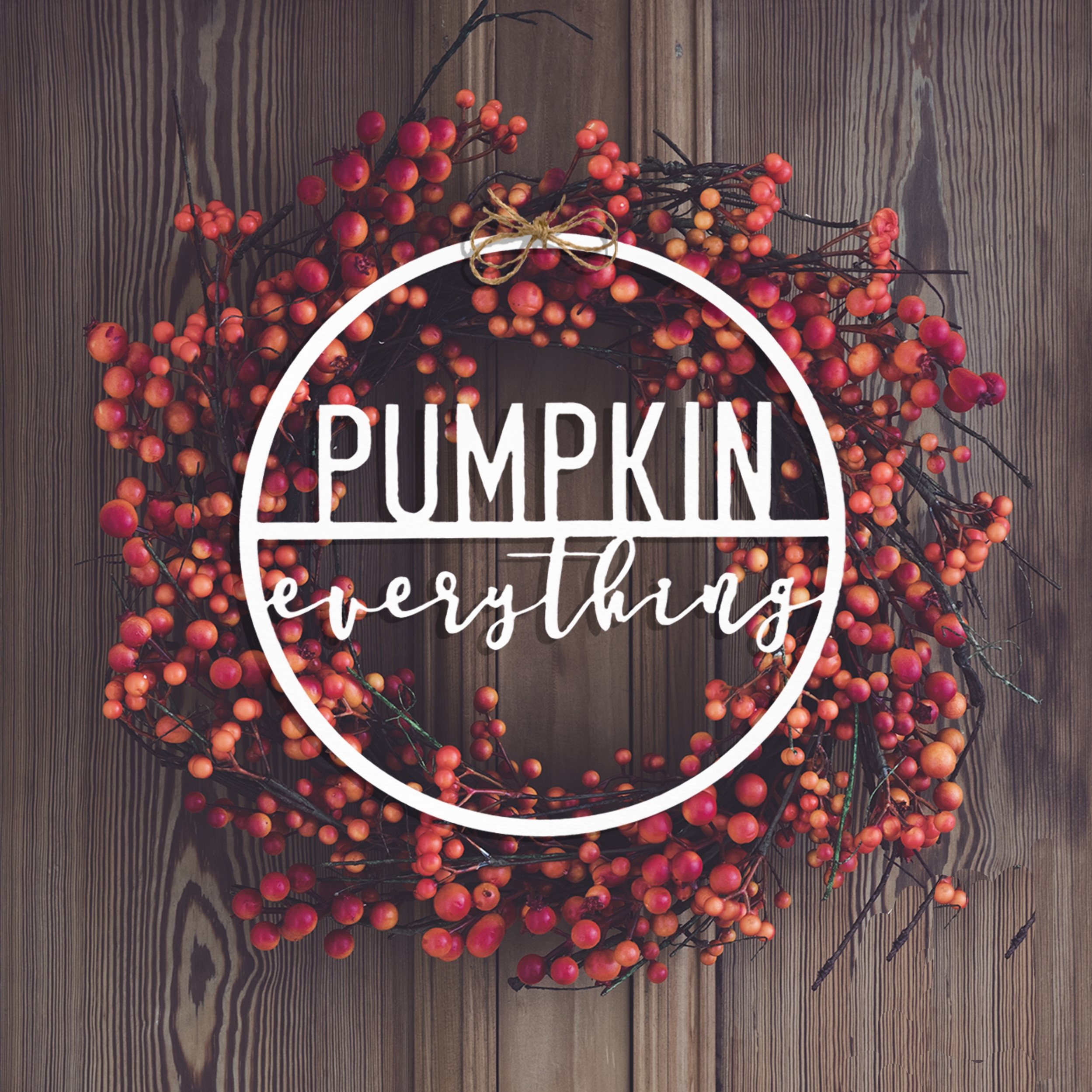 A wreath of red berries on a wooden background with the text \“PUMPKIN everything\“ across the center.