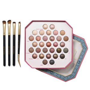 An eyeshadow palette with multiple shades ranging from neutrals to dark tones, accompanied by four makeup brushes.