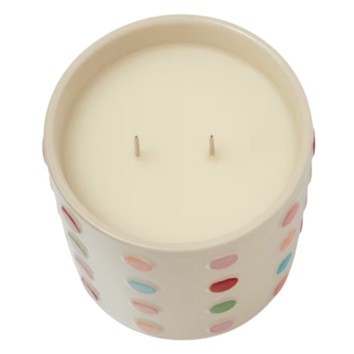 A two-wick candle in a round ceramic container, decorated with colorful polka dots on the exterior.