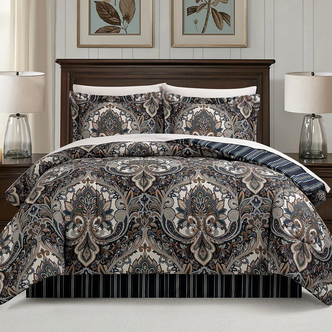 A bedding set featuring a paisley pattern in neutral tones is displayed with matching pillow shams, set in a well-lit bedroom with dark wood furniture and minimalistic decor, including two table lamps and botanical artwork above the bed.
