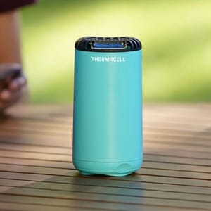 A teal Thermacell mosquito repellent device on a wooden surface.