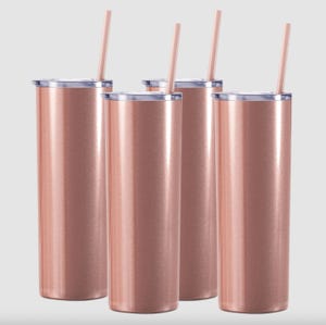 Four identical insulated tumblers with a metallic rose gold finish, each accompanied by a straw and a clear lid.