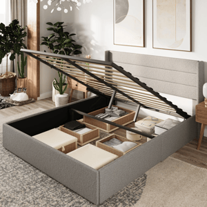 A bed frame with hydraulic lift-up slats reveals a storage compartment underneath, containing organized wicker baskets and neatly folded fabrics. The room includes modern decor and plants.
