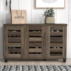 A wooden shoe cabinet with a slatted door design is topped with a paper shopping bag labeled \“Market 29\“ and a potted plant.