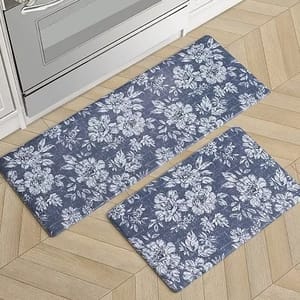 Two floral-patterned kitchen mats in blue and white are placed on a light wood herringbone floor.