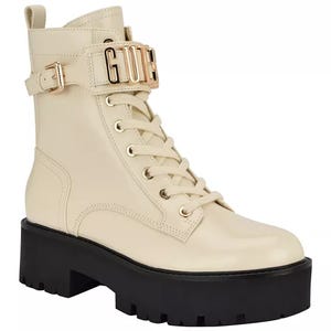 GUESS Vaires Lug Sole Combat Booties feature a cream-colored upper with lace-up detailing and a prominent logo strap around the ankle, paired with a thick black lug sole for added height and traction.