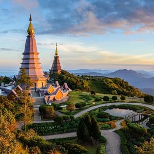 Two pagodas on a mountain with beautifully landscaped gardens and a scenic view of mountains in the background.