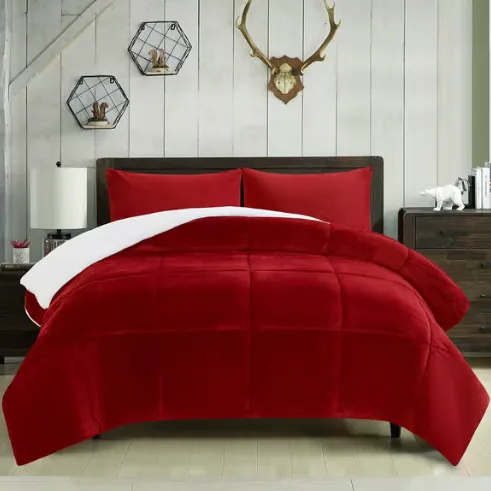 A red comforter set with reversible white lining is displayed on a bed, accompanied by matching pillows. The room decor features a wooden headboard, two modern hexagonal shelves, an antler wall mount, and a bedside table with a white lamp and decor items.