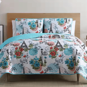A quilt and pillow set with a Parisian-themed design featuring the Eiffel Tower, flowers, and streetlamps in red, blue, and green colors.