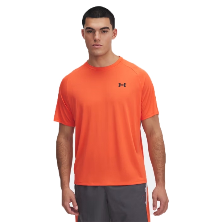 A man is wearing an orange Under Armour T-shirt with a small logo on the chest and gray athletic shorts.