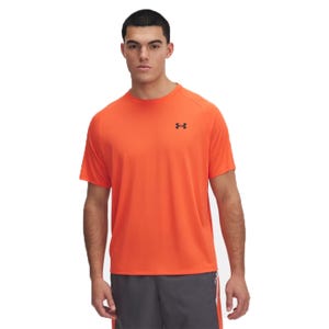 A man is wearing an orange Under Armour T-shirt with a small logo on the chest and gray athletic shorts.