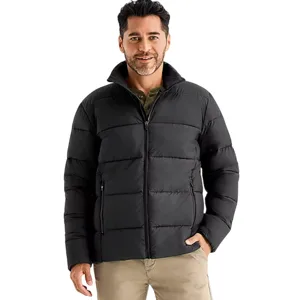 A man is wearing a black puffer jacket with a front zipper and side pockets, paired with beige pants.