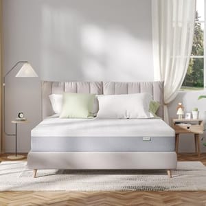 A bedroom setup with a neatly made bed featuring a gray and white mattress, modern bedside tables, a floor lamp, and light curtains by the window allowing natural light in.
