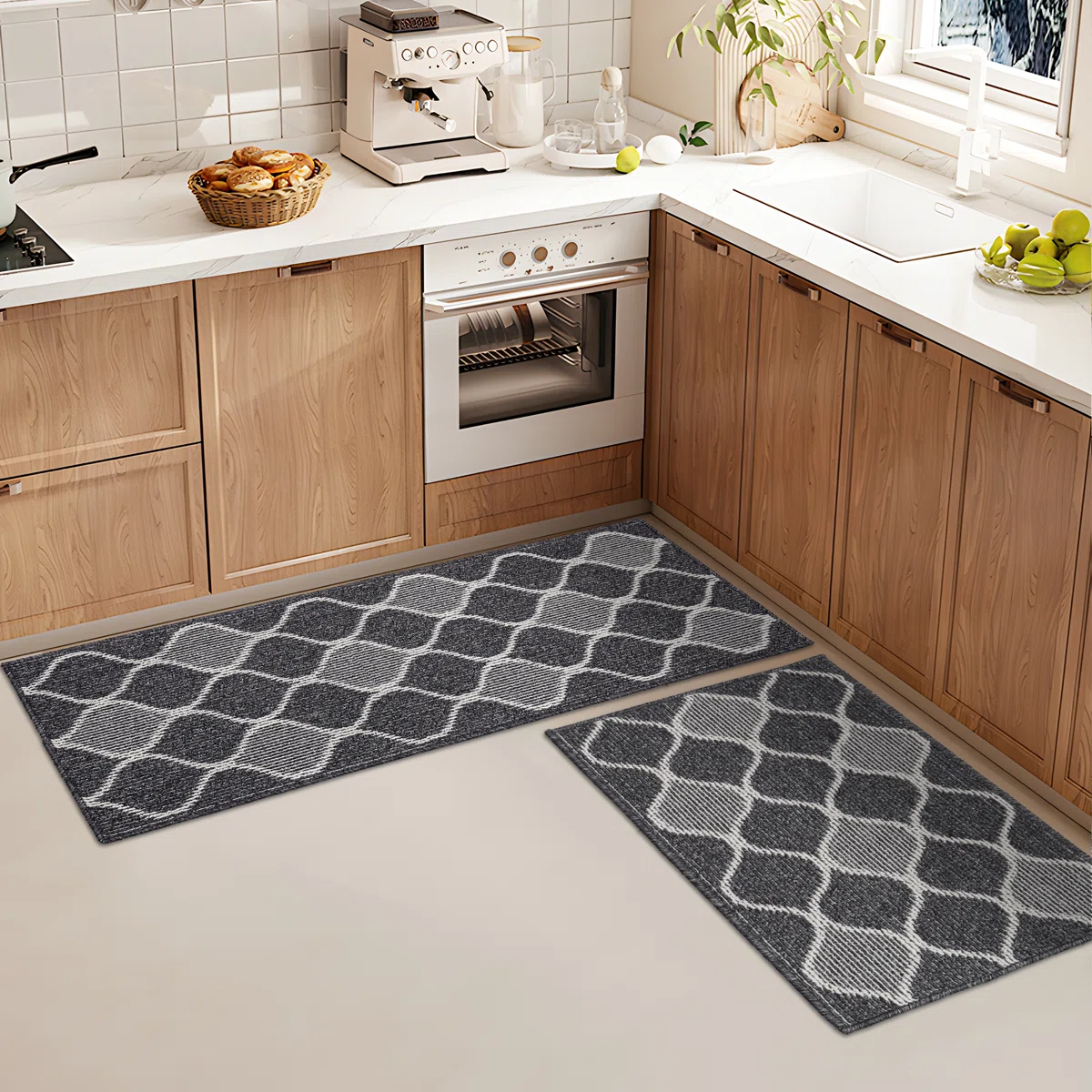 Two gray kitchen rugs with a geometric pattern are placed on the floor in front of wooden cabinets and a white countertop.