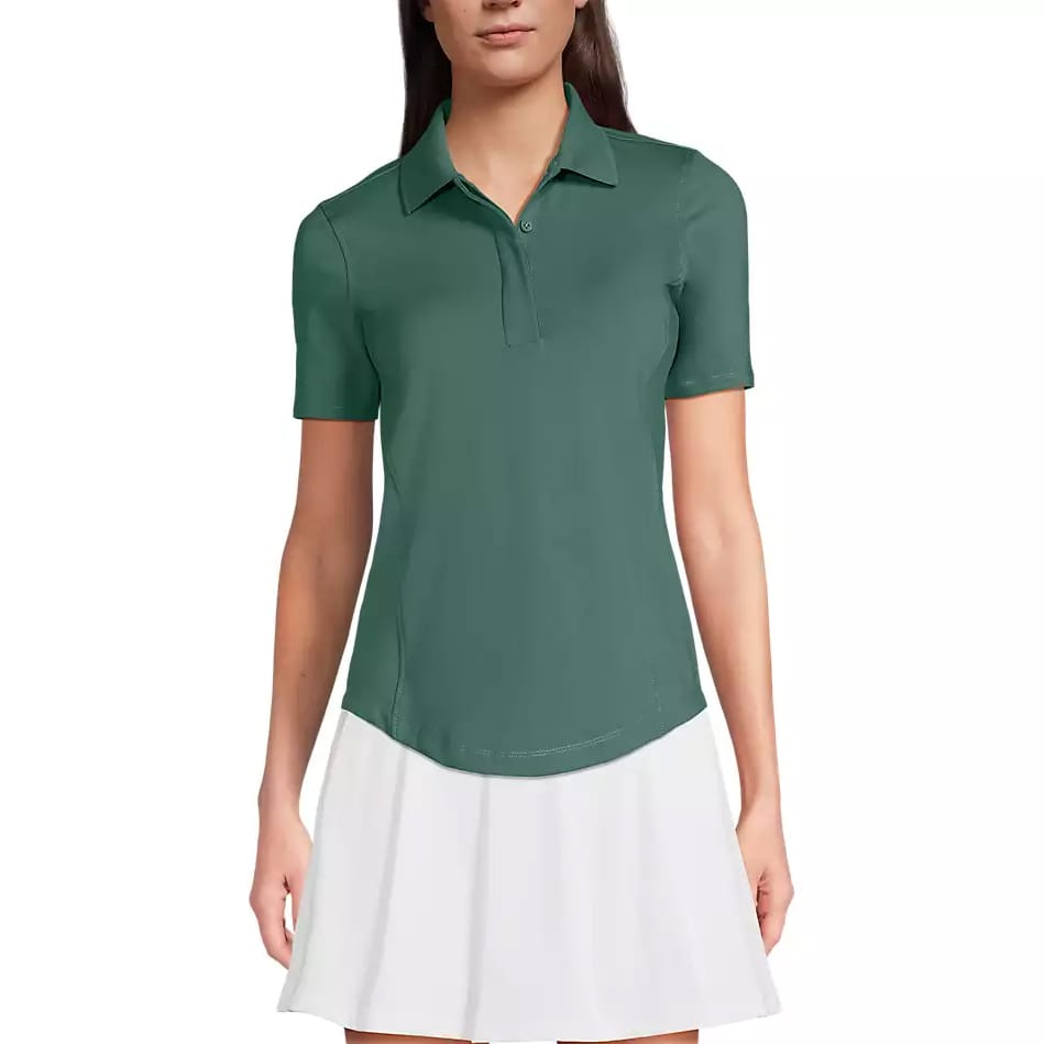 A woman is wearing a green short-sleeve polo shirt paired with a white skirt.