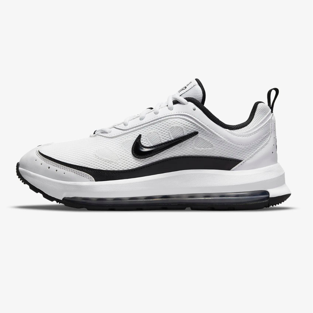 White Nike Air Max AP shoes with a black Nike swoosh logo, a black outsole, and visible Air Max cushioning in the heel.
