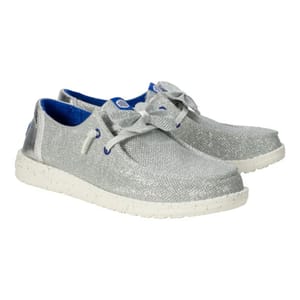 Hey Dude Wendy Sparkle Bow Shoes feature a glittery silver fabric with blue lining, white speckled sole, and a bow on each shoe for a casual, stylish look.