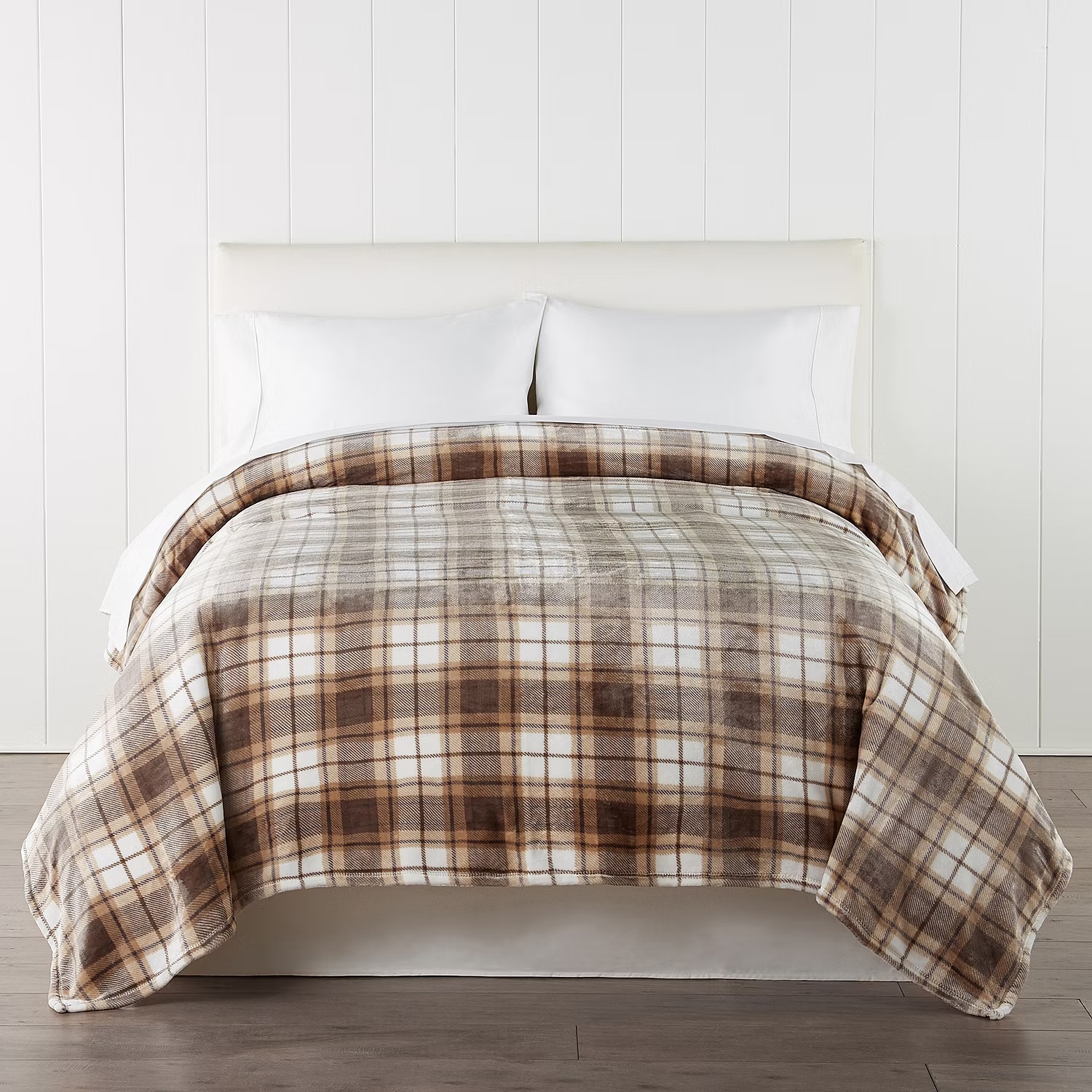 A neatly made bed with crisp white sheets and a brown plaid comforter.