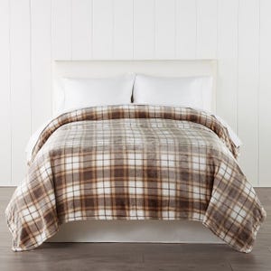 A neatly made bed with crisp white sheets and a brown plaid comforter.