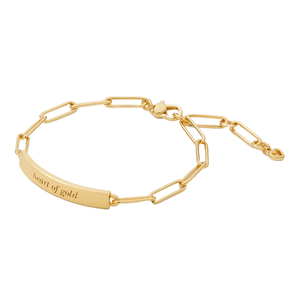 Gold bracelet with a rectangular ID plate inscribed \“heart of gold,\“ featuring a chain-link design and adjustable clasp.