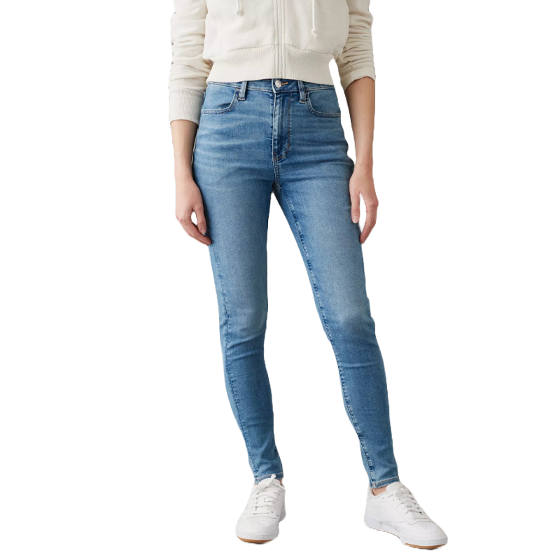 A person is wearing light blue skinny jeans with a white casual jacket and white sneakers.
