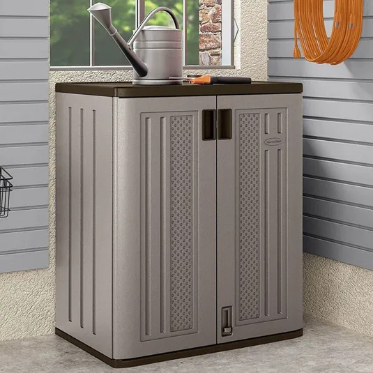 Compact gray storage cabinet with double doors in a garage setting, featuring a watering can on top and coiled hose on the wall.