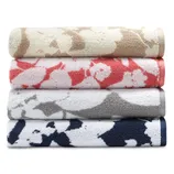 Four rolled towels with abstract floral patterns in beige, coral, gray, and navy.