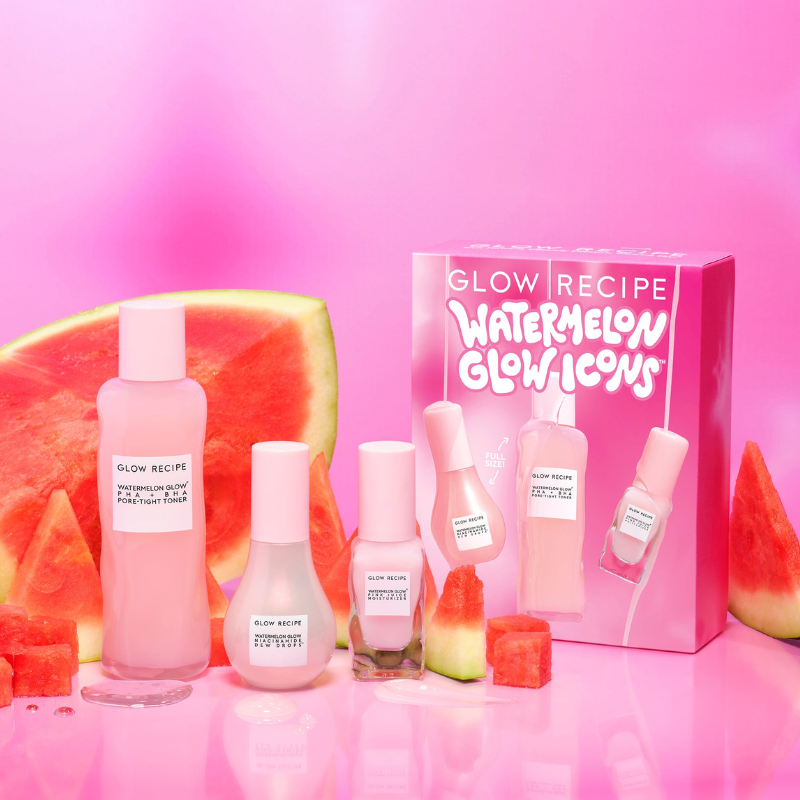 A collection of Glow Recipe skincare products, featuring watermelon-themed packaging, is displayed alongside fresh watermelon slices on a pink background.