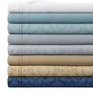 A stack of folded, patterned bed sheets in various colors, including white, blue, gray, green, and beige.